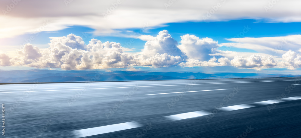 Motion blurred asphalt road and mountain with cloud scenery.