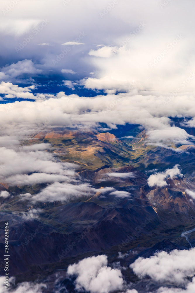 Aerial view above the clouds and mountain peaks on a sunny day.