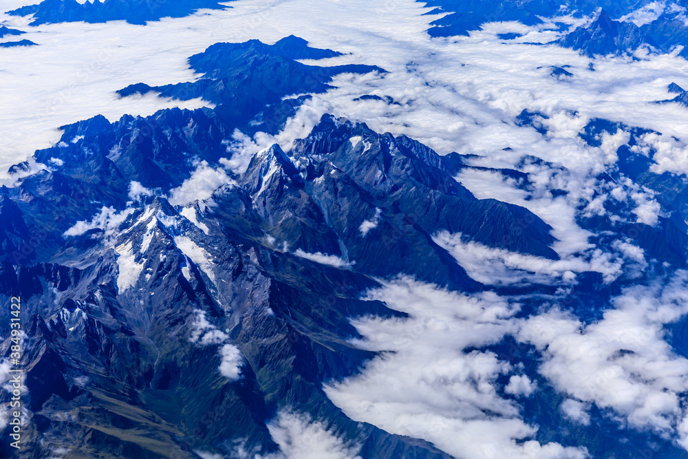 Aerial view above the clouds and mountain peaks on a sunny day.