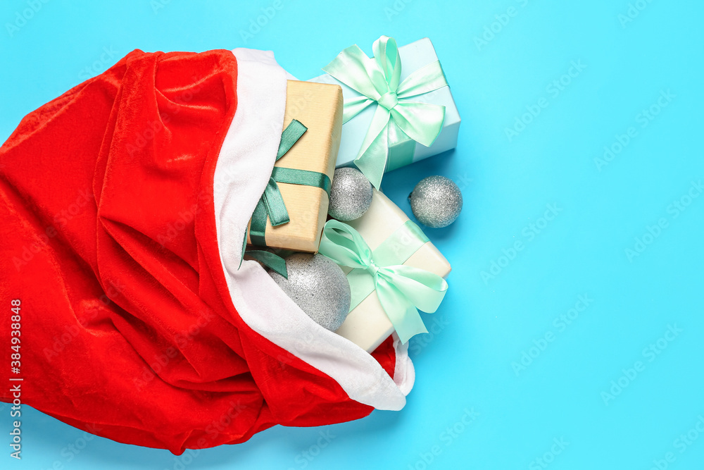 Santa bag with gifts on color background