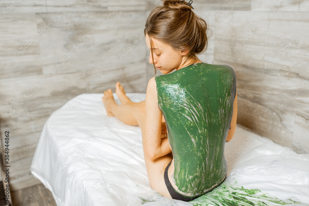 Portrait of a beautiful young woman during mud treatment at spa