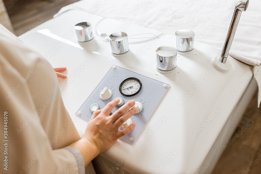 Spa worker presses buttons during procedure in balneology with carbon dioxide bath, close-up