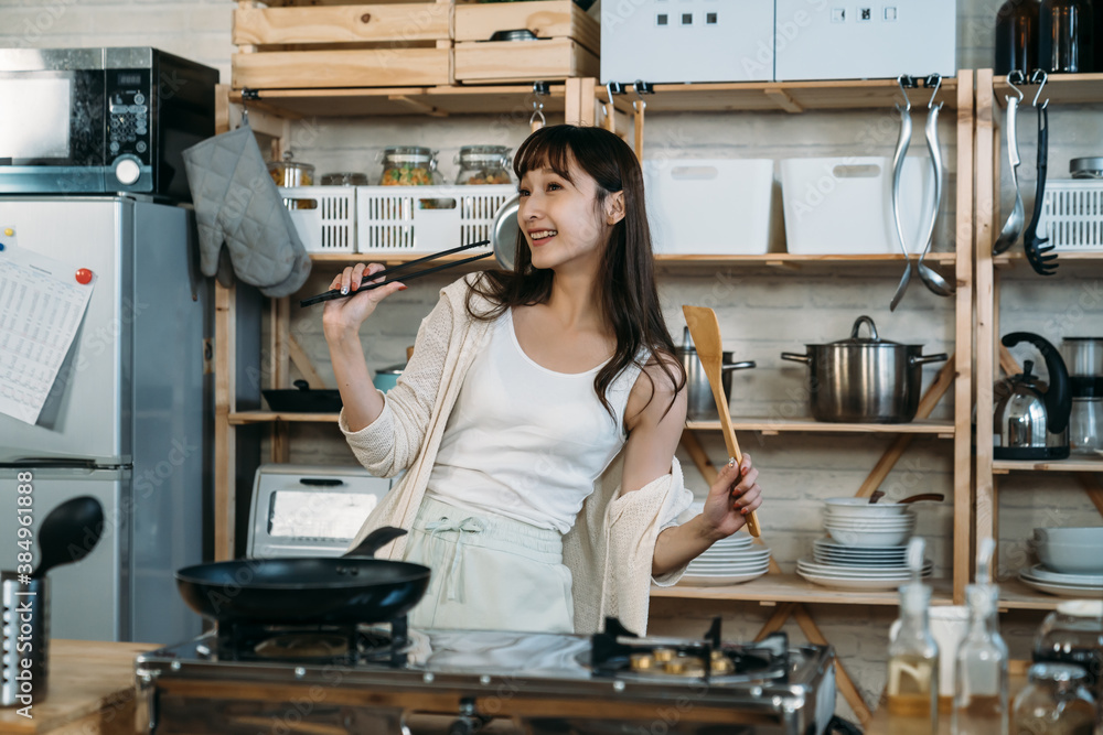 Happy Asian Japanese holding the chopstick and spatula dancing in the kitchen, enjoy the relaxation 