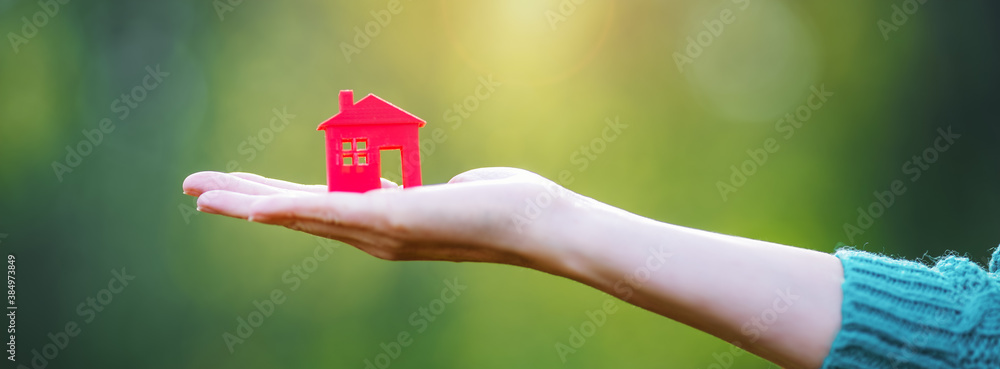 Model of small red house in the human hand.