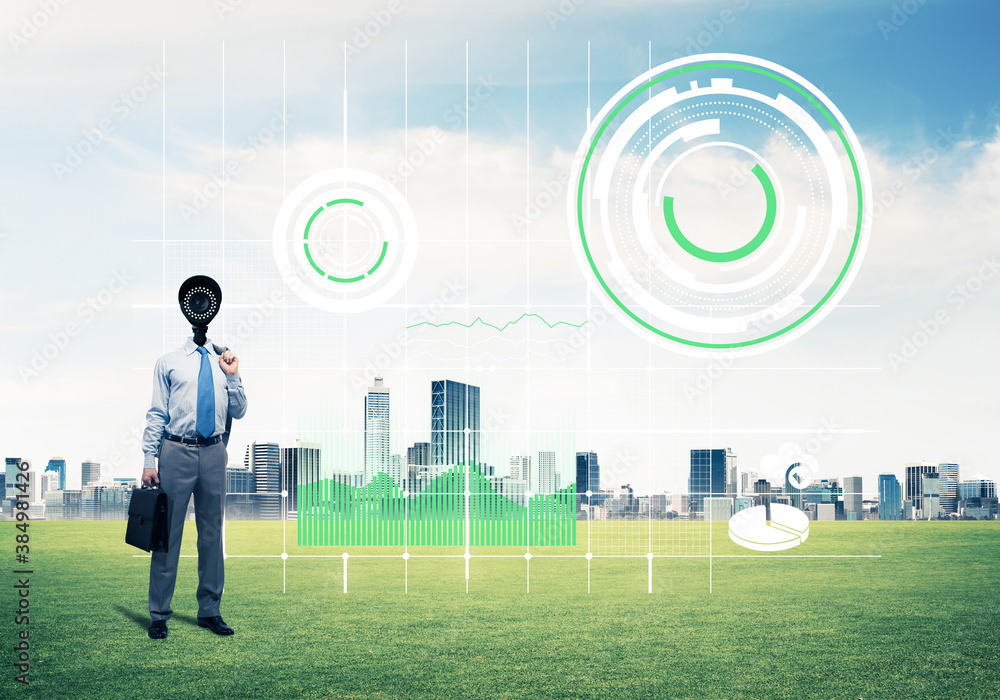 Camera headed man standing on green grass against modern cityscape