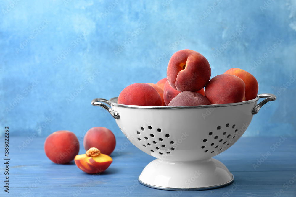 Sweet peaches in colander on table