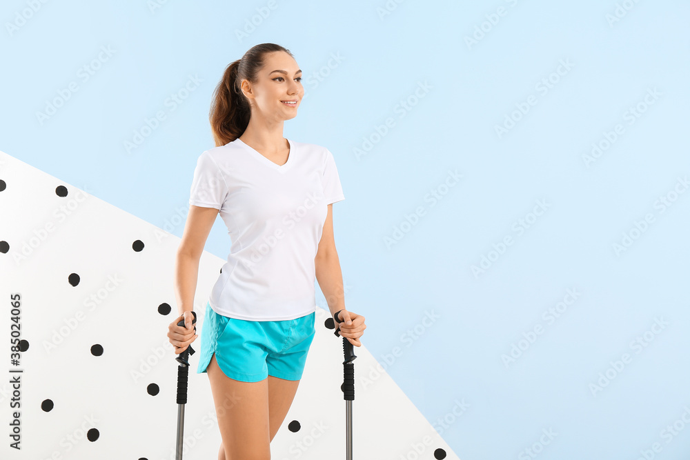 Young woman with walking poles on color background