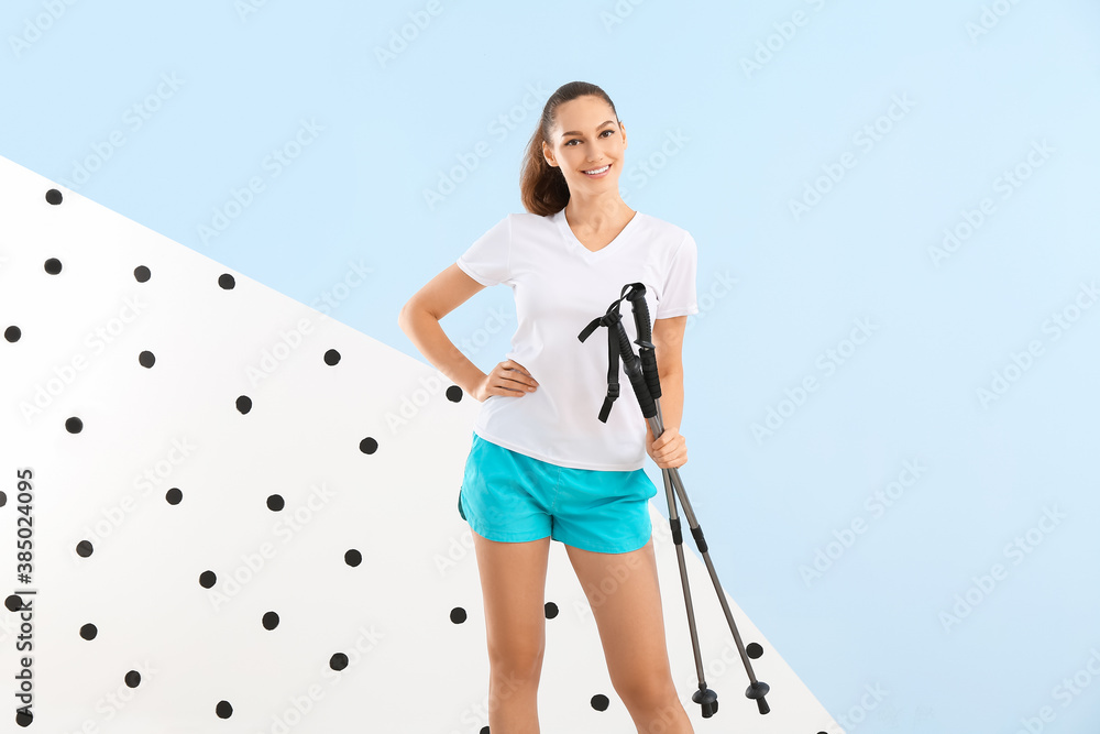 Young woman with walking poles on color background