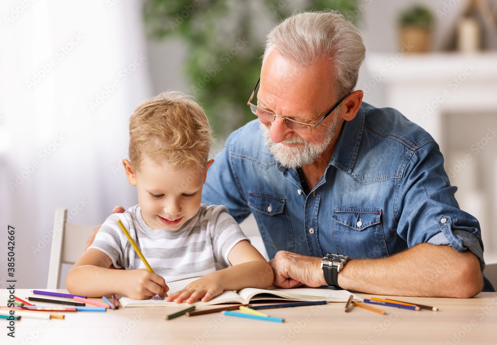 Cheerful boy drawing with grandfather.