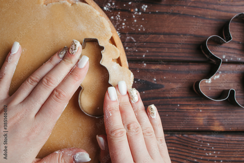 Woman cutting cookies of raw gingerbread dough