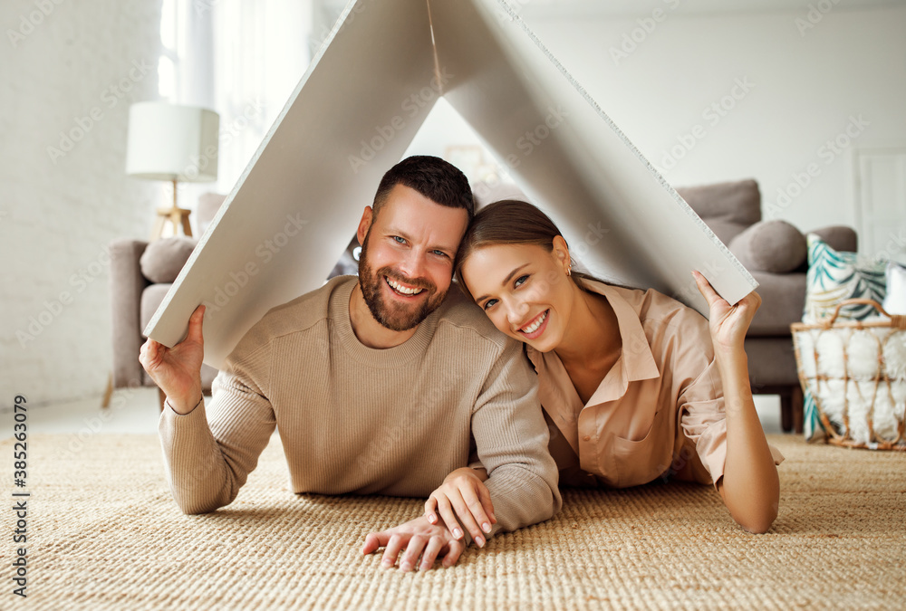 concept housing  young family couple.  man and woman under fake roof in  new home