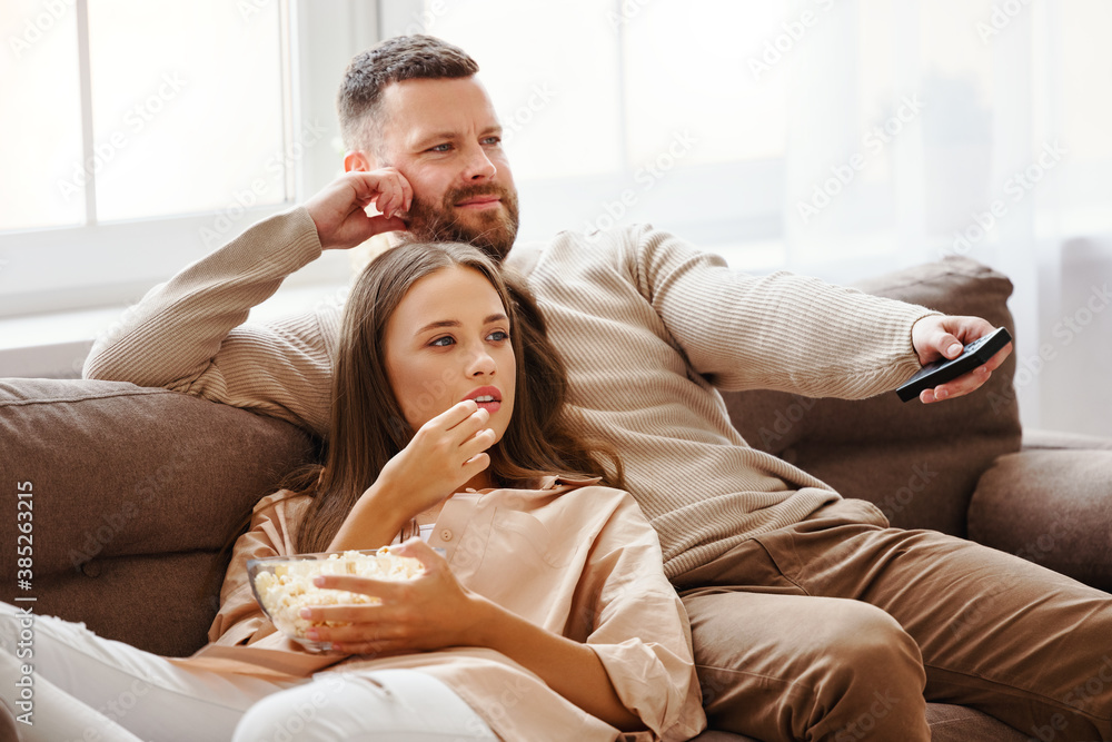 Family couple watching television at home on sofa