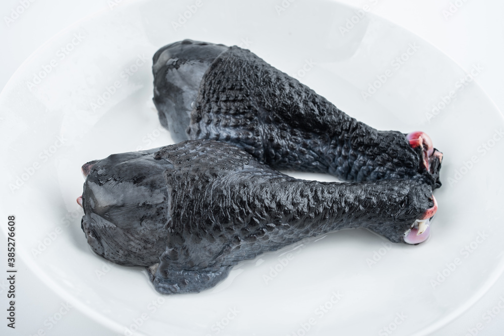 Two fresh black chicken drumsticks on white background