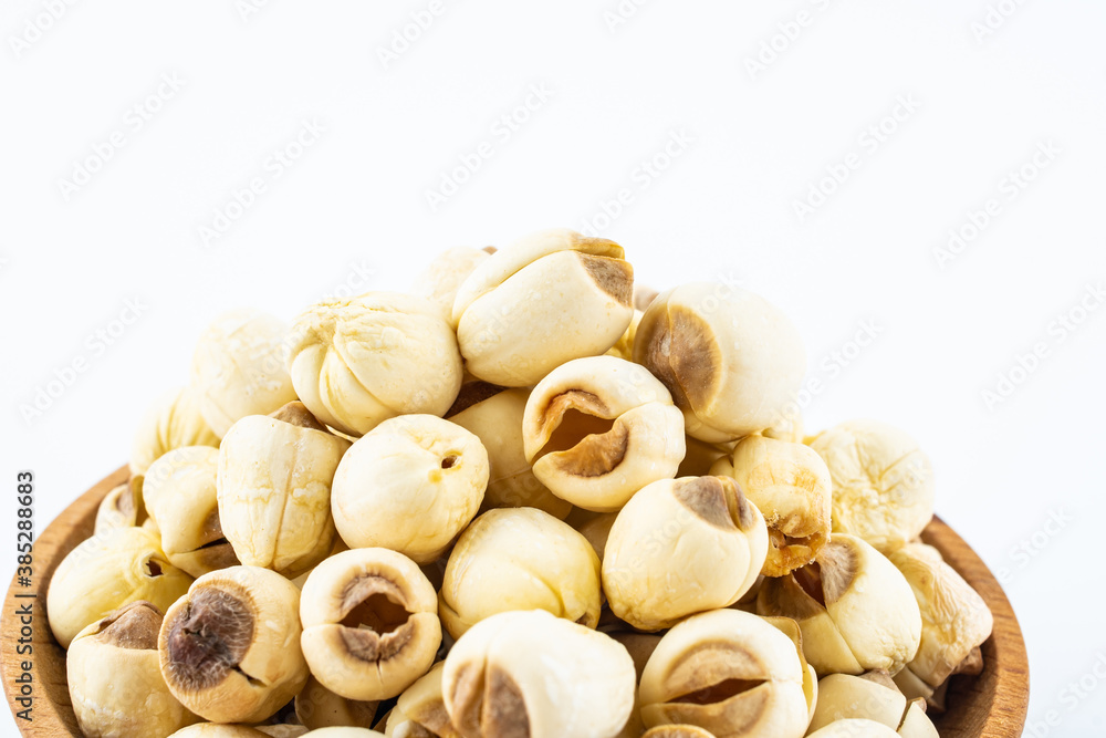 Dried white lotus seeds in a saucer on white background