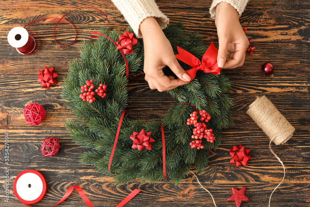 Woman making beautiful Christmas wreath on table