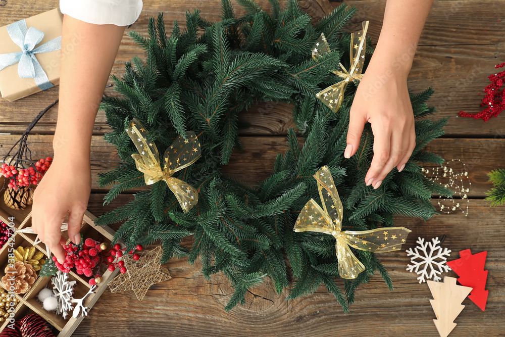 Woman making beautiful Christmas wreath on table