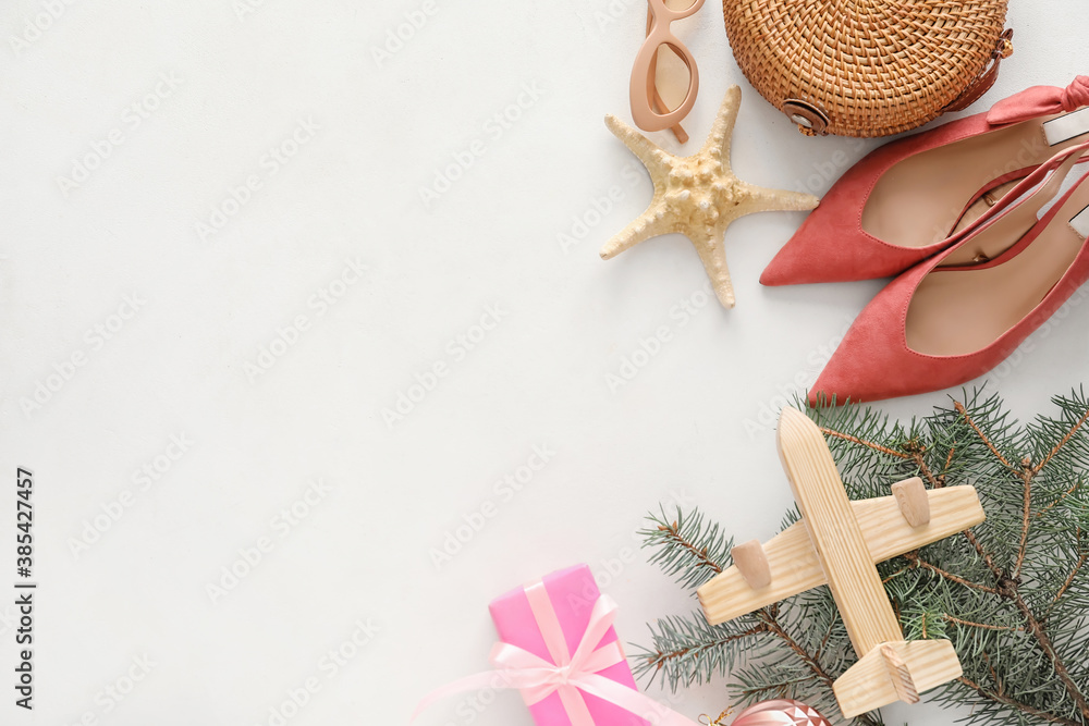 Composition with Christmas decor, airplane and female accessories on white background