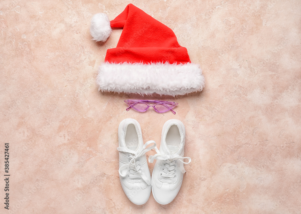 Santa hat with eyeglasses and shoes on color background