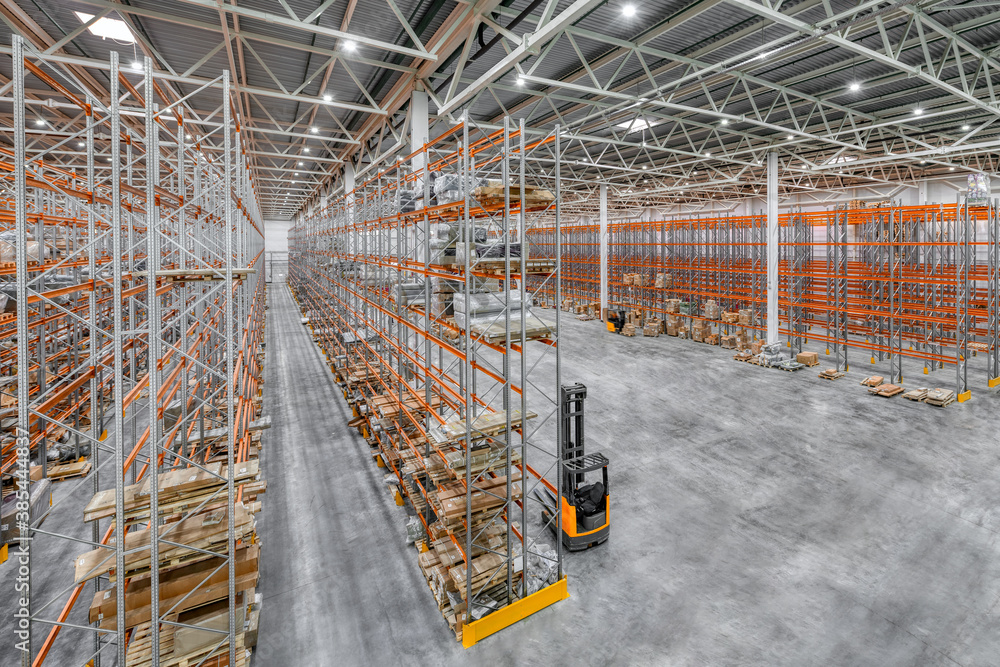 Large warehouse. Tall and long metal racks filled with various boxes, containers and drawers