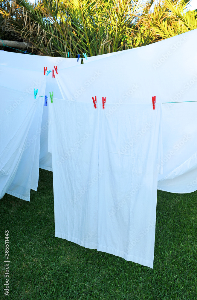 White sheets drying in the sun on an outdoor clothesline