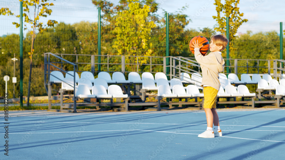 Little boy playing basketball in summer