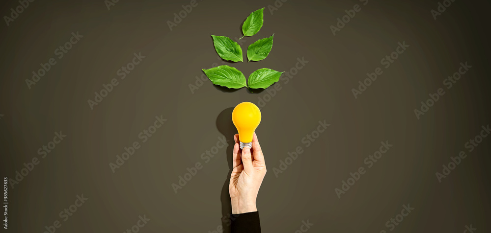 Person holding a light bulbs with green leaves