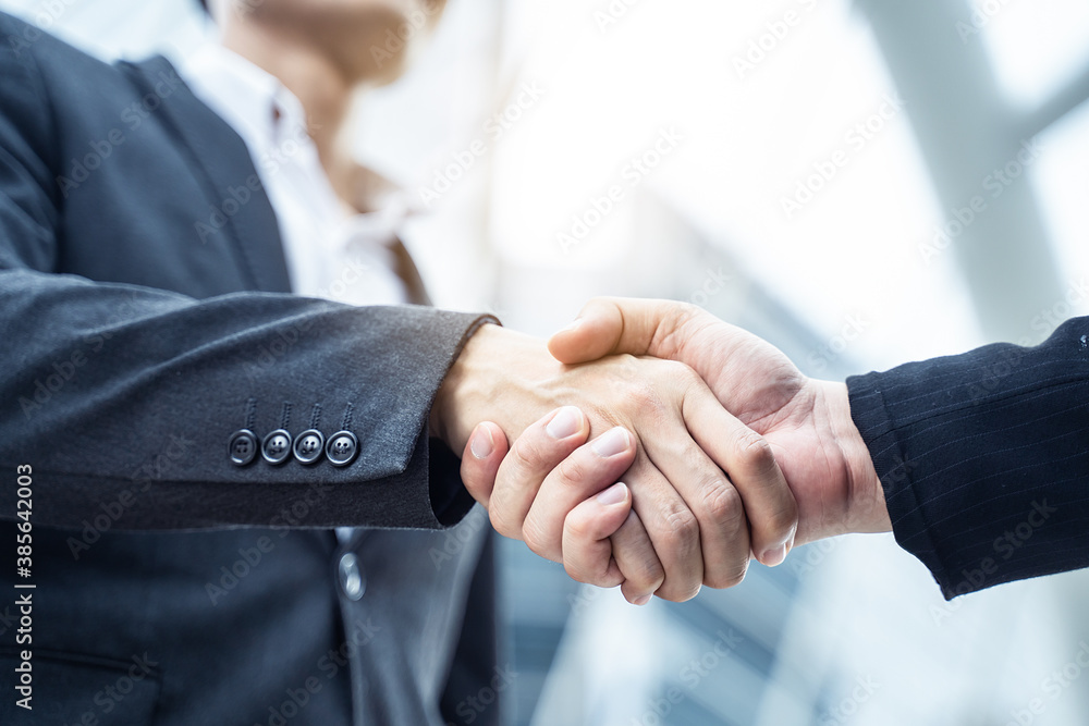 Asian businessmen making handshake in city with building background.