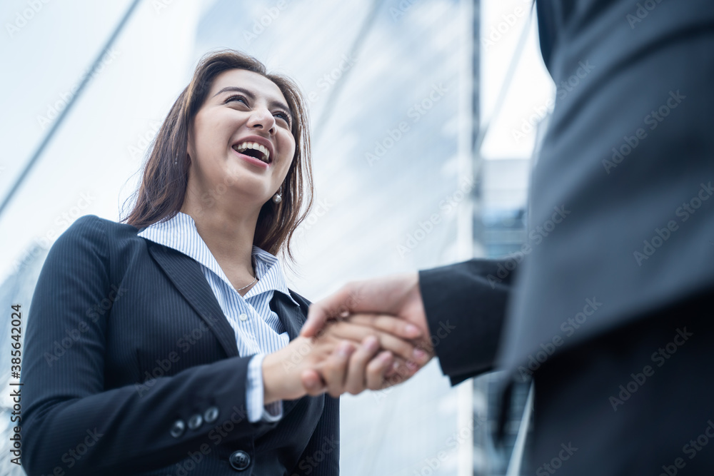 Asian businesswoman make handshake in city with building background.