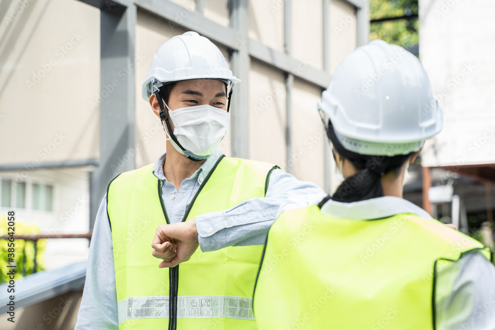 Asian young engineer man and woman greeting each other by elbow touch.