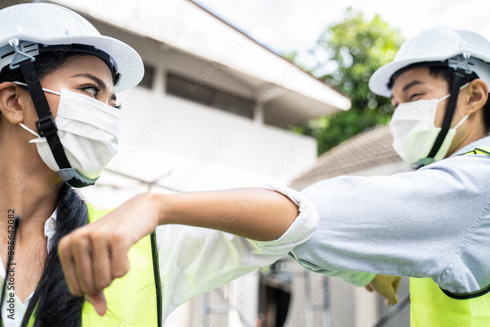 Asian young engineer man and woman greeting each other by elbow touch.