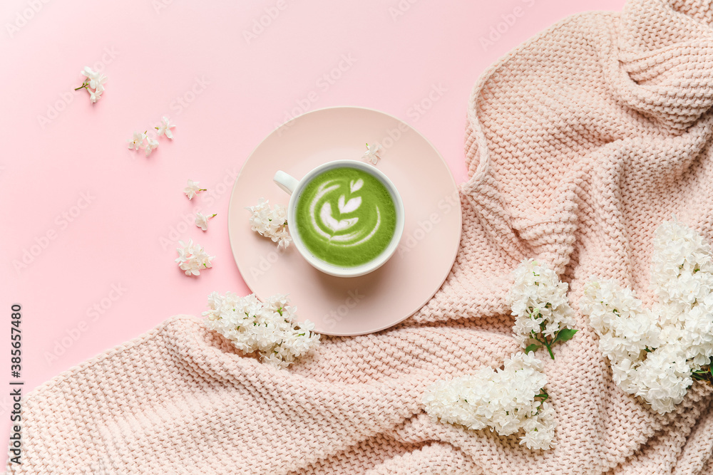 Beautiful composition with cup of matcha tea and lilac flowers on color background