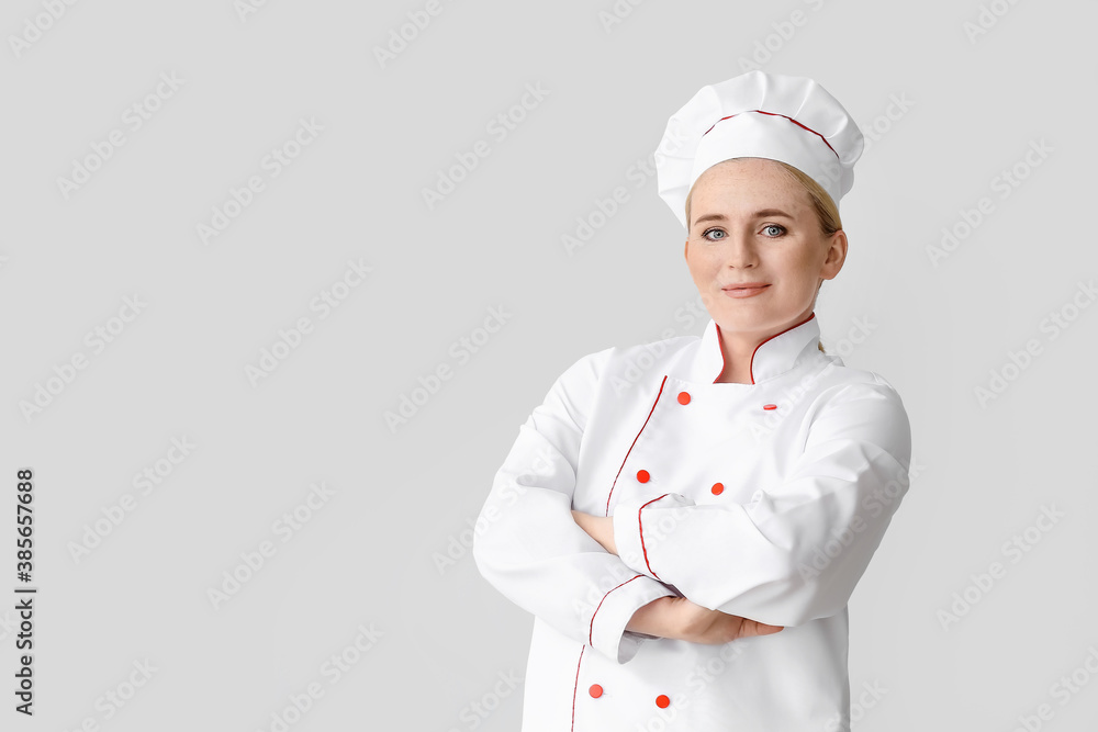 Mature female chef on grey background