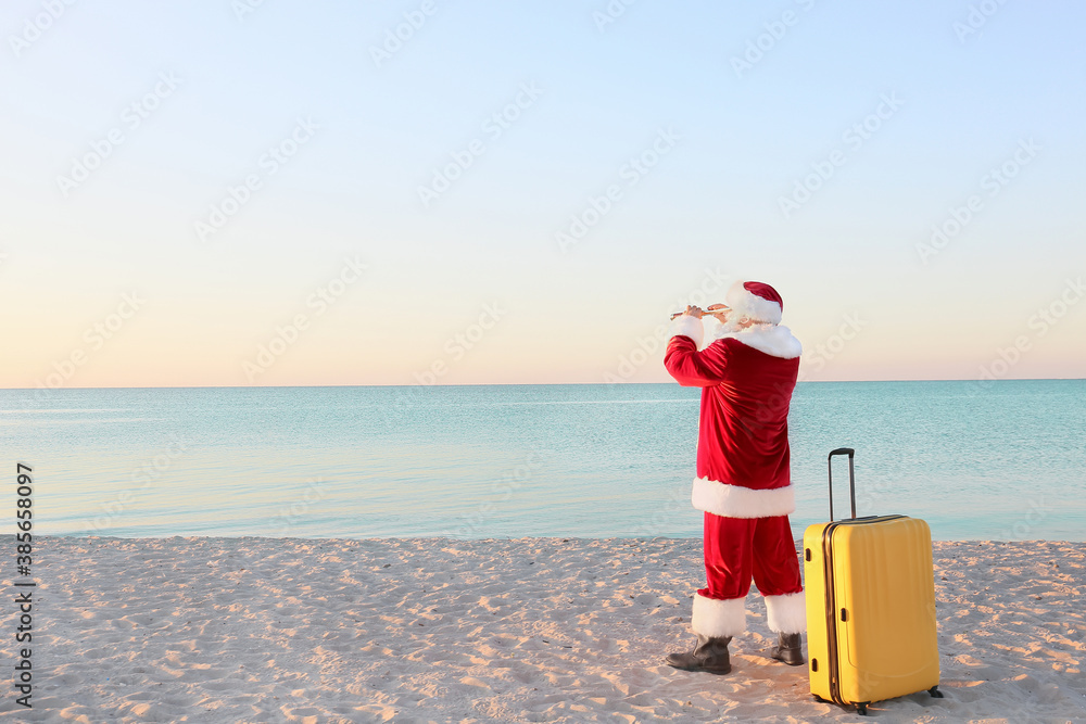 Santa Claus with luggage at sea resort. Christmas vacation