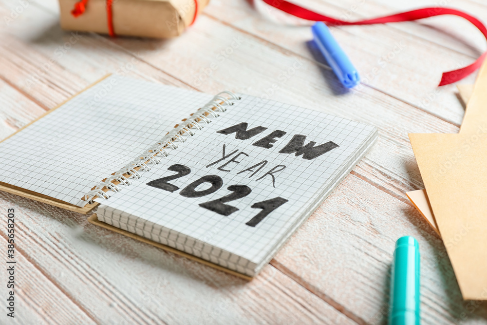 Notebook with text NEW YEAR 2021 on wooden background