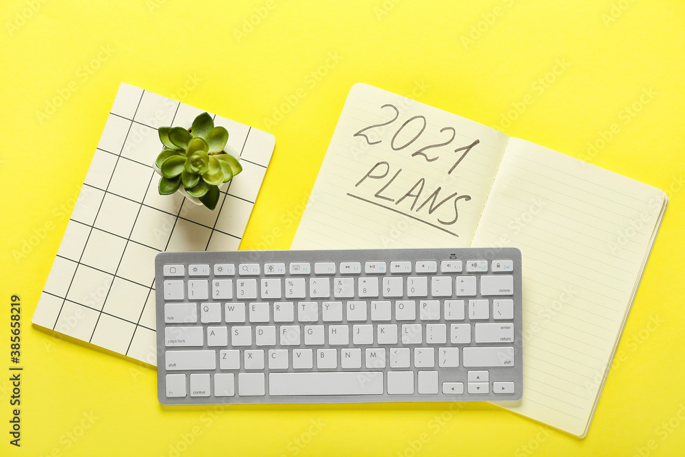 Notebook with text 2021 PLANS and PC keyboard on color background