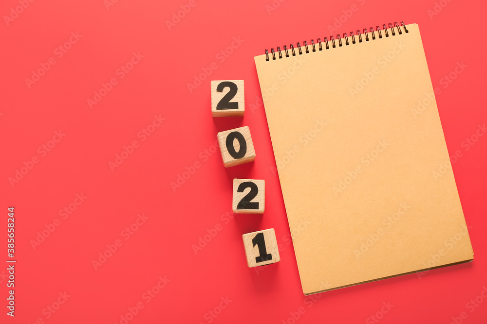 Notebook and cubes with figure 2021 on color background