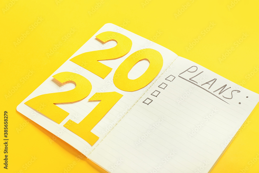 Notebook with word PLANS and figure 2021 on color background