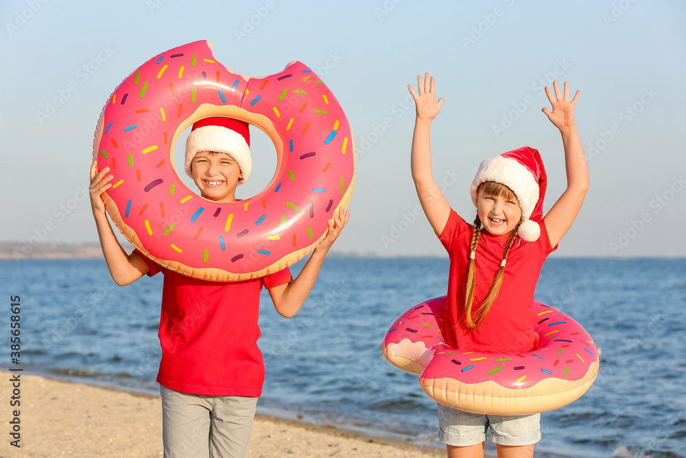 Happy children with inflatable rings celebrating Christmas at tropical resort