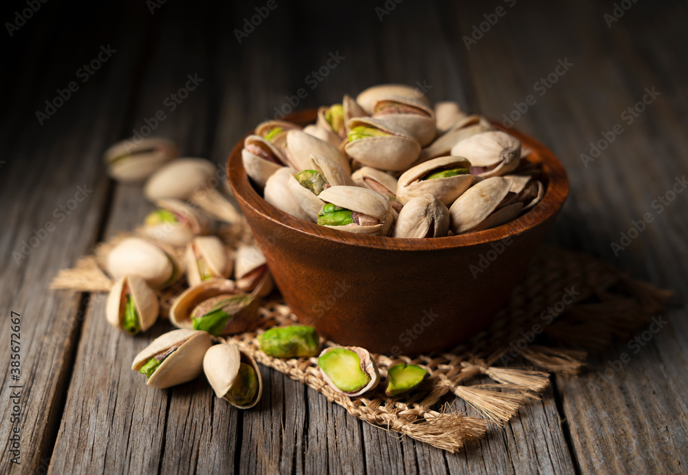 Pistachios in a bowl set against an old wooden backdrop