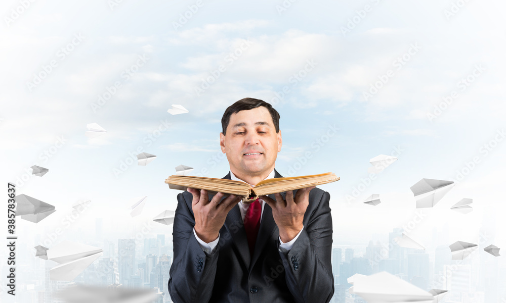 Serious businessman holding open old book