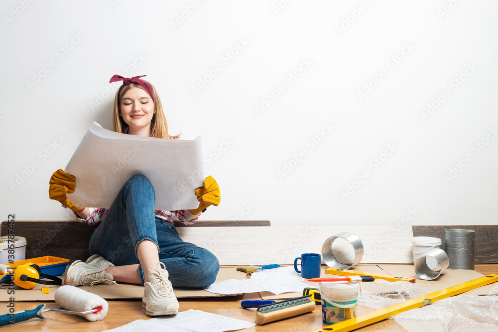 Happy woman sitting on floor with blueprint