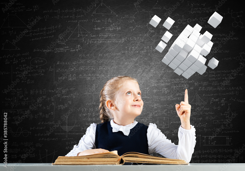 Smiling little girl sitting at desk with open book