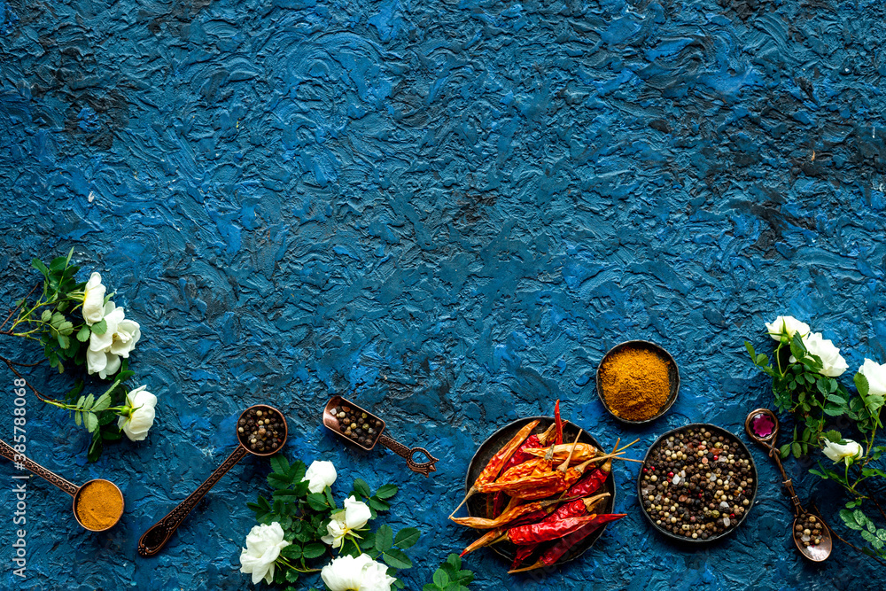 Set of spices and herbs for cooking in metal spoons and bowls, top view