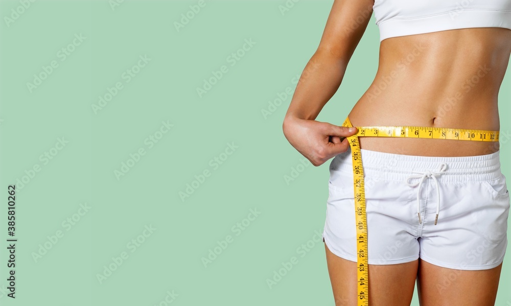 Slim young woman measuring her thin waist with a tape measure