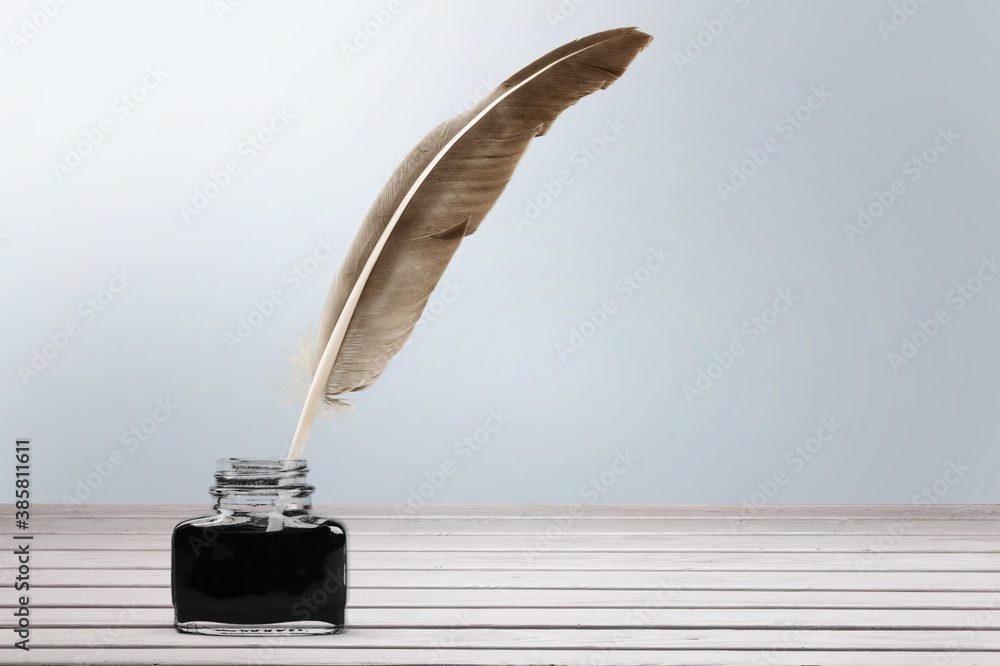 Feather quill pen and glass inkwell