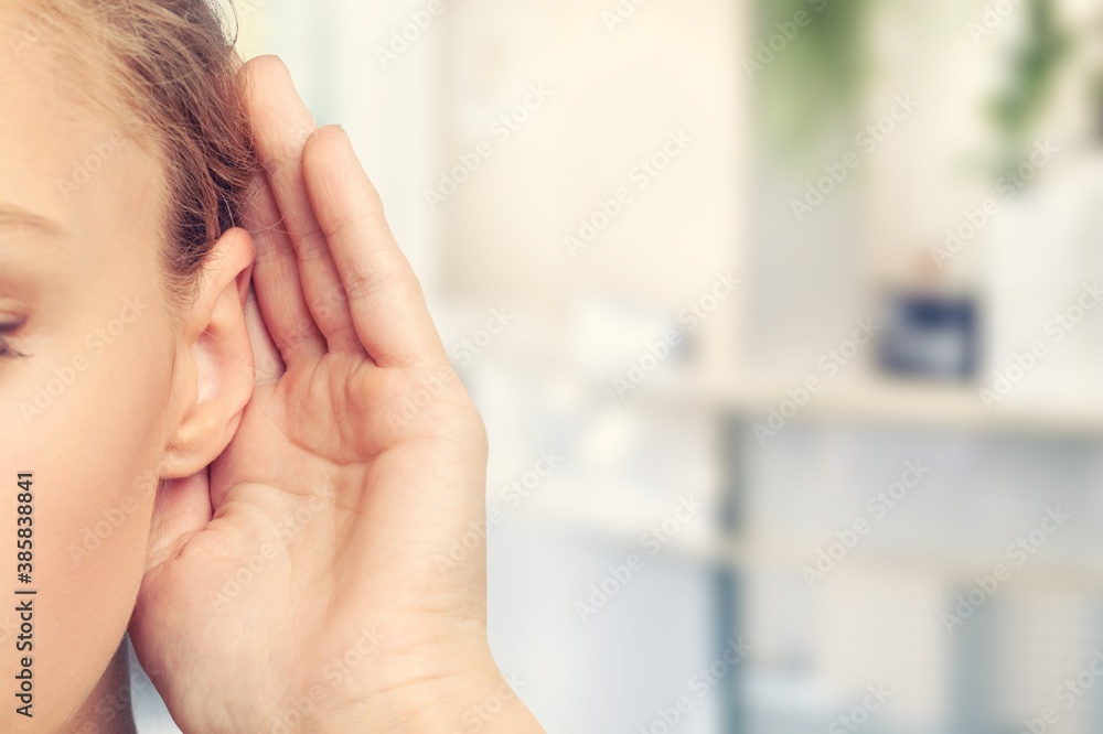 A woman holds hand near her ear and listening to something