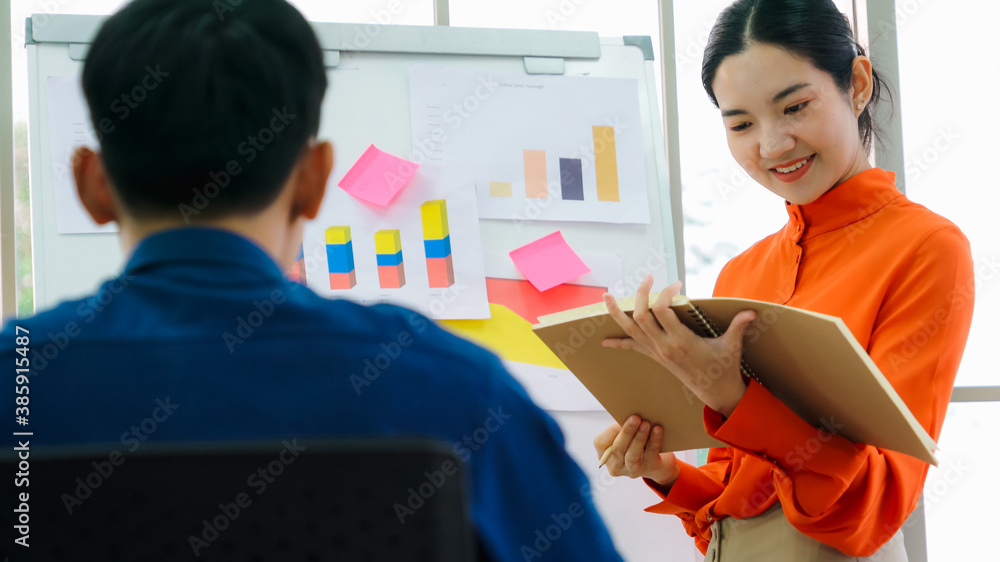 Young woman explains business data on white board in casual office room . The confident Asian busine