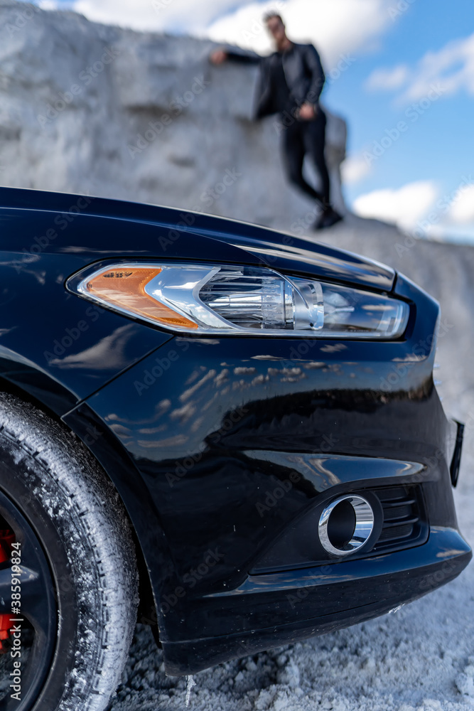 Selective focus of luxury car on front view. Headlights and part of tire. White quarry background. S