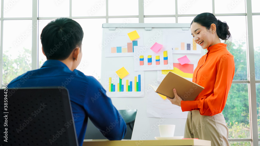 Young woman explains business data on white board in casual office room . The confident Asian busine