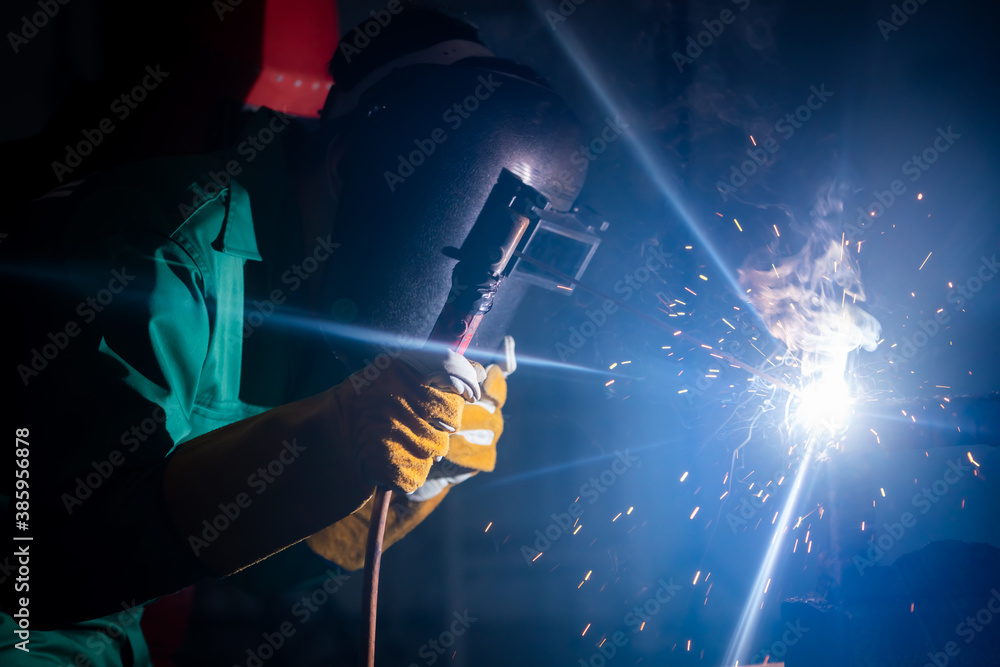 Metal welding steel works using electric arc welding machine to weld steel at factory. Metalwork man